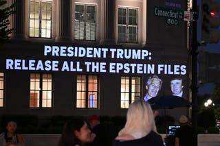 People walk by as a message projected onto the US Chamber of Commerce building across from the White House in Washington, DC, on Friday